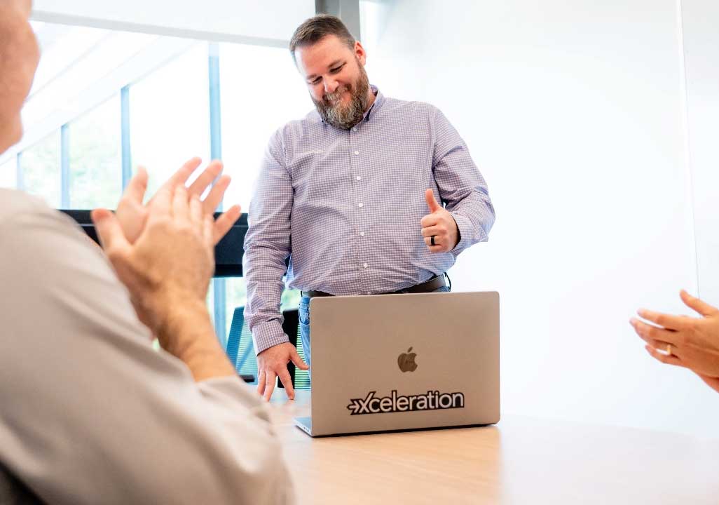 Employee giving a thumbs-up while colleagues clap