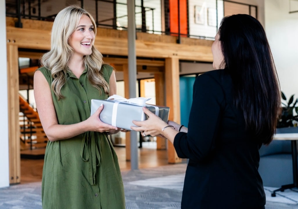 Employee receiving a wrapped gift from a coworker to mark a work anniversary